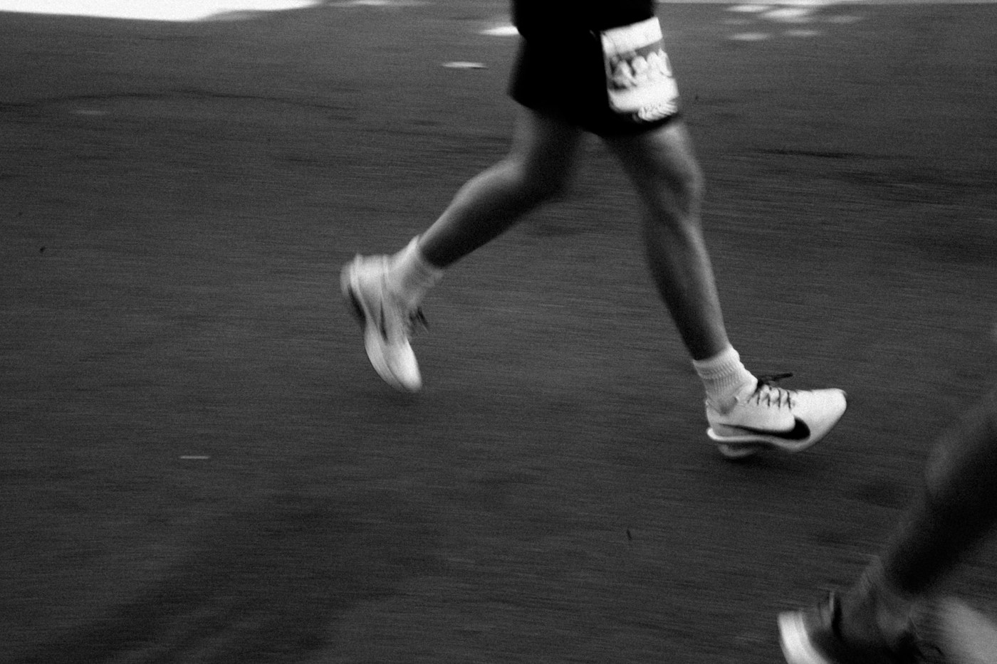 Beine und Laufschuhe von Laufenden in Bewegung